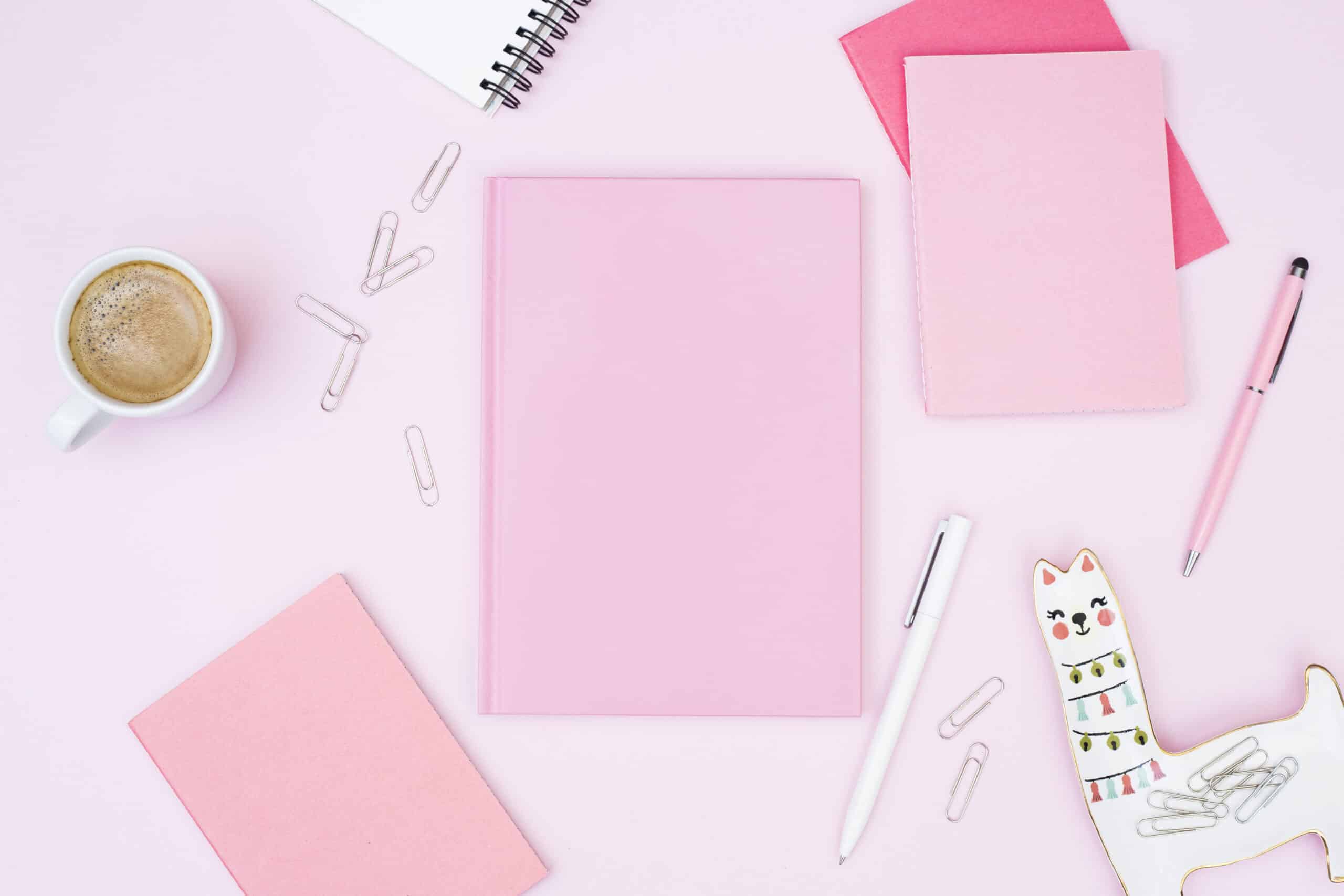 Agenda rosa con elementos rosas alrededor como libretas y bolis