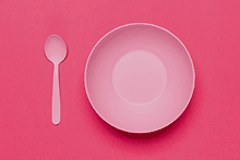 Plato y cuchara rosas sobre un fondo rosa