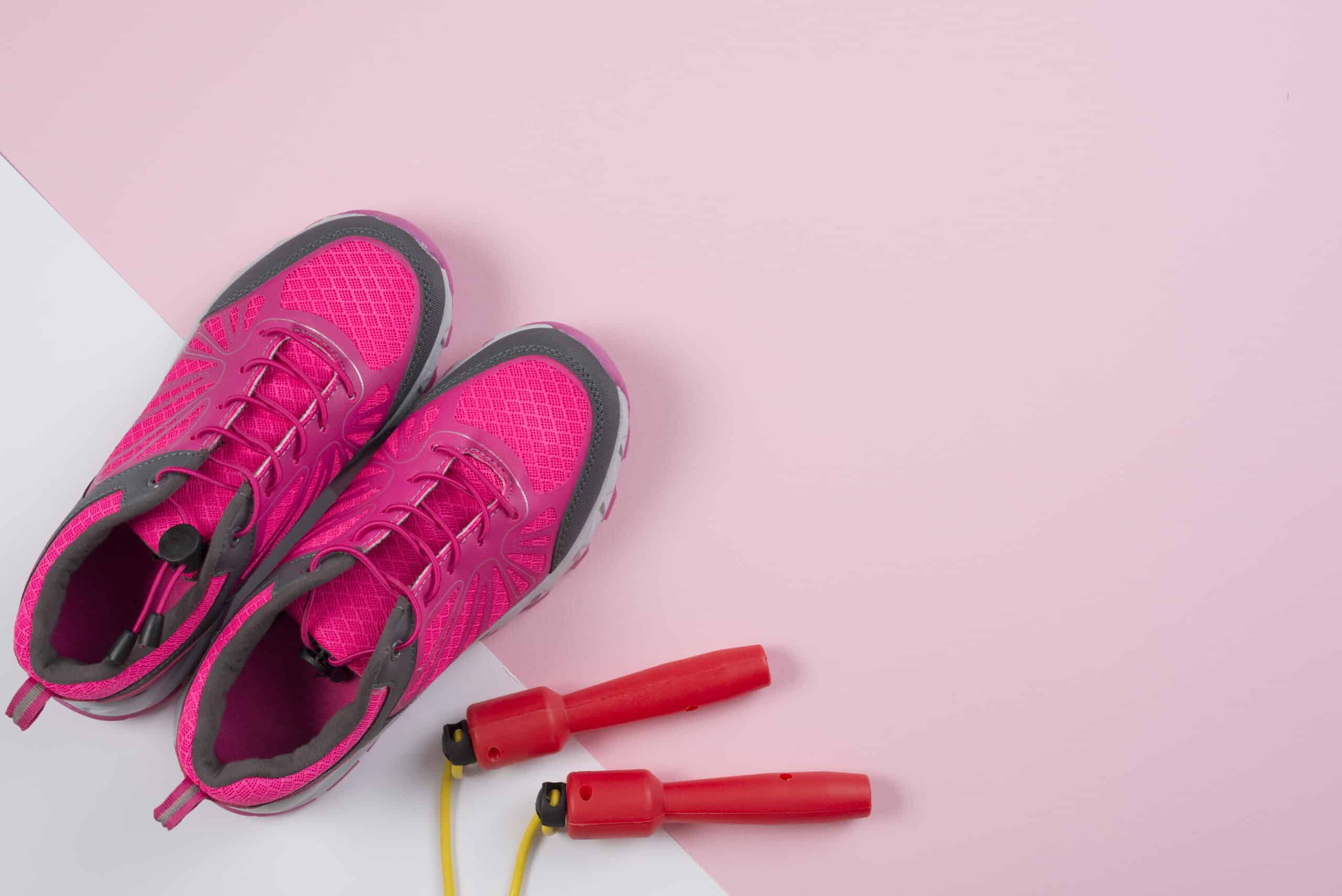 Zapatillas rosas con una comba rosa al lado sobre un fondo rosa