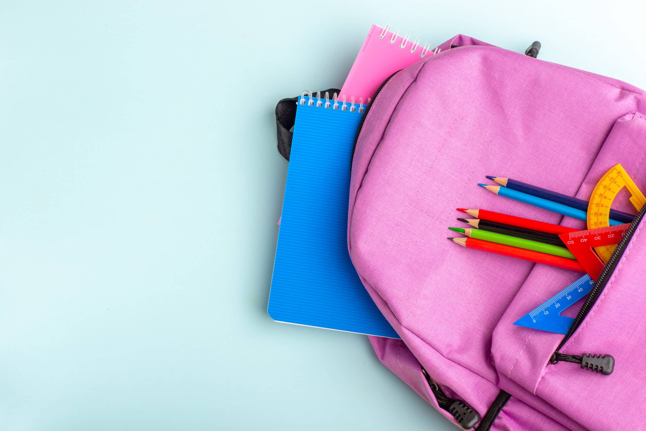 Mochila rosa sobre fondo rosa con libros de colores rosa y marornes