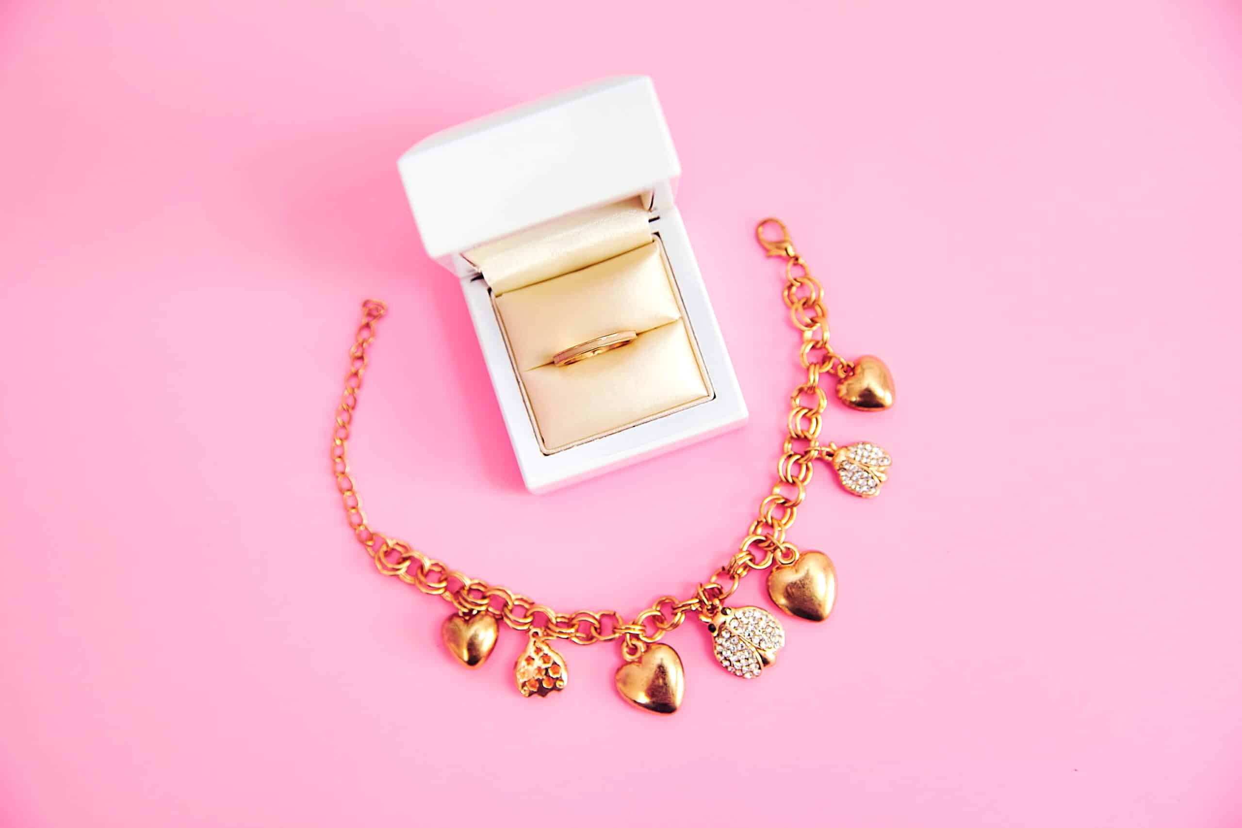 Pulsera y anillo sobre fondo rosa
